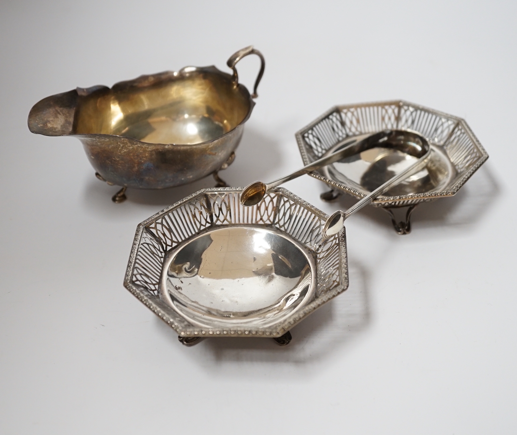 A George V silver sauce boat, Adie Bros. Birmingham, 1925, a pair of George V pierced silver bonbon dishes, Mappin & Webb, Birmingham 1930, 10.2cm and a pair of Georgian silver sugar tongs.